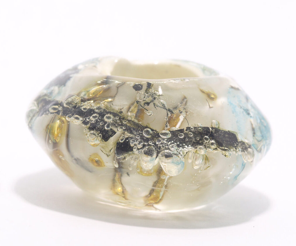 a mini universe of ivory glass bead with metal inclusions